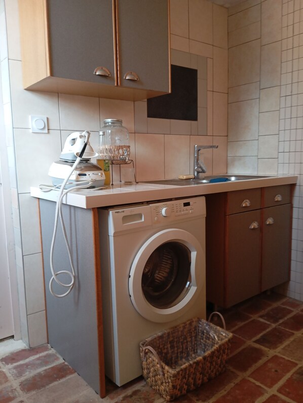 A compact kitchen with a built-in washing machine, a sink, and cabinets.