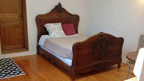 Una cama de madera con cabecera, una mesita de noche y un buró.