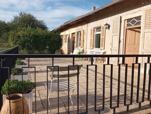 A balcony with a metal railing, a wooden bench, and a potted plant.