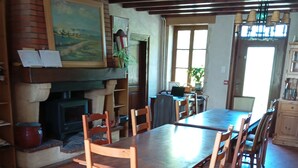 Un comedor con una gran mesa de madera y sillas, una chimenea y una estantería.