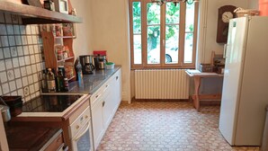 Una cocina con piso de baldosas, un refrigerador, una estufa y una ventana con vista al exterior.