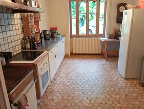 Una cocina con piso de baldosas, un refrigerador, una estufa y una ventana con vista al exterior.