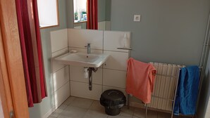 Un baño con lavamanos blanco, un espejo, un inodoro y un radiador.