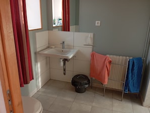 Un baño con lavamanos blanco, un espejo, un inodoro y un radiador.