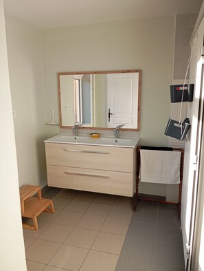 A bathroom with a double sink, wooden cabinet, and a towel rack.