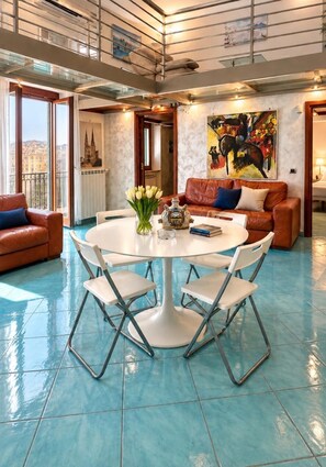A spacious living area with a round table, two sofas, and a large painting. - Heart of Naples (Napoli)