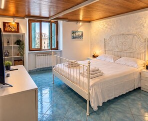 A bedroom with a bed, bedside tables, a desk, and a window with shutters. - Heart of Naples (Napoli)