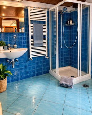 Un baño con ducha, lavabo y suelo de baldosas.