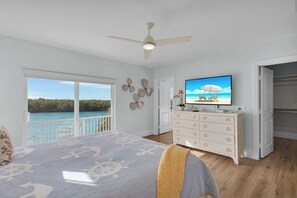 Una camera da letto con un letto, una cassettiera, una televisione e vista sulla spiaggia.