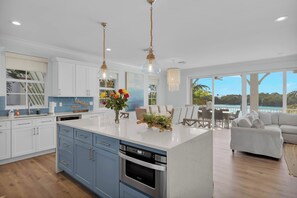 A modern kitchen with a central island, a dining area with a view, and a living room with a sofa. - Luxury Waterfront 5BD/4Bth private pool 36' dock (Marathon)