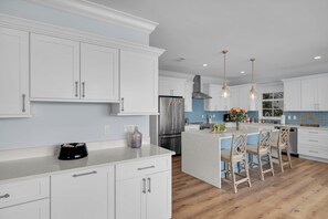 A modern kitchen with white cabinetry, stainless steel appliances, and a central island with bar stools. - Luxury Waterfront 5BD/4Bth private pool 36' dock (Marathon)