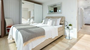 A modern bedroom with a large bed, a bedside table with a lamp, a mirror above the bed, and a door leading to another room. - Houseboat in Kappeln With Swimming Pool (Kappeln)