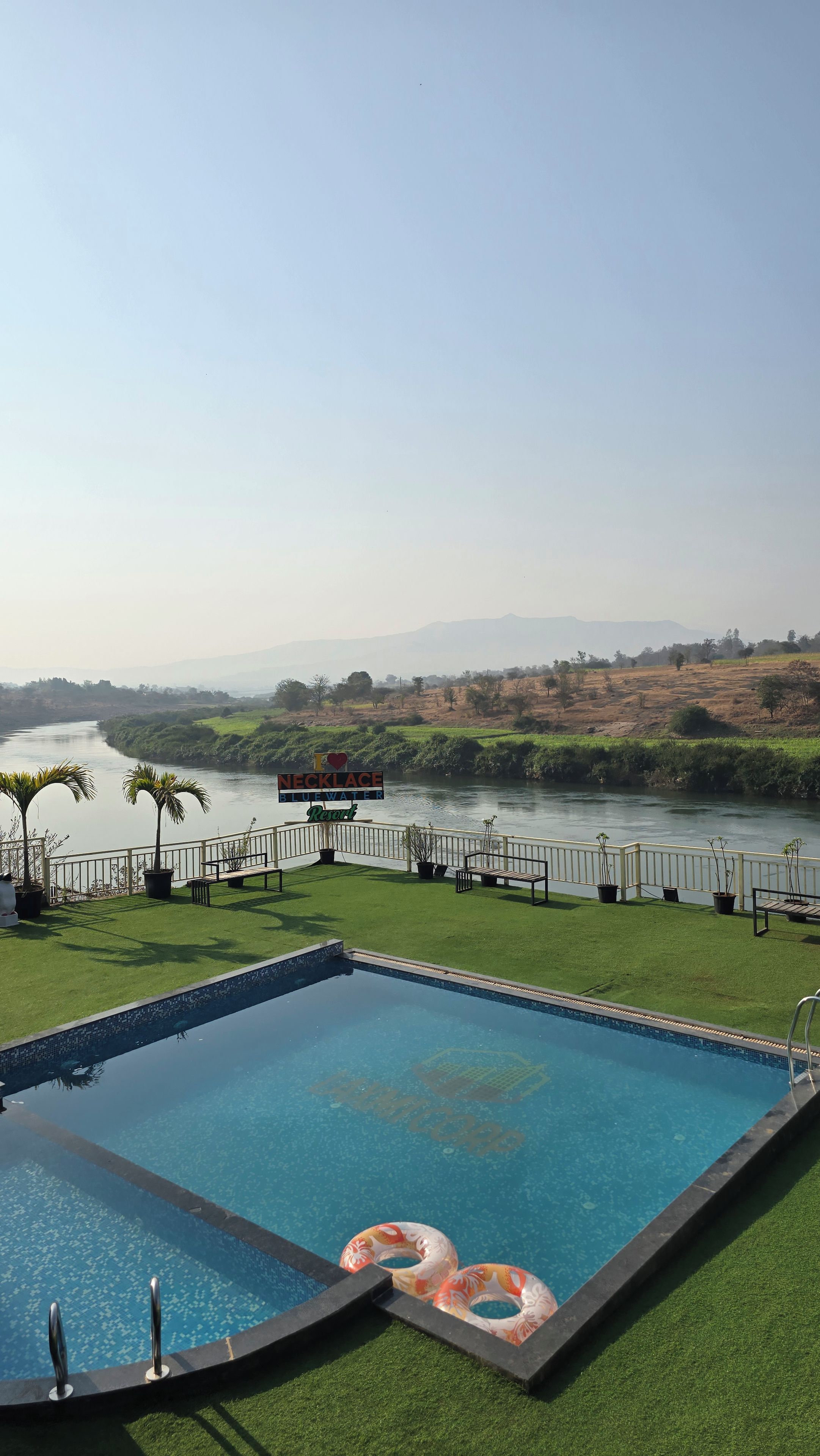 Una piscina con vista a un río y colinas lejanas.