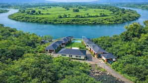 A riverside hotel with multiple buildings, a swimming pool, and lush greenery. - Necklace Bluewater Resort Bhor (Sangamner)