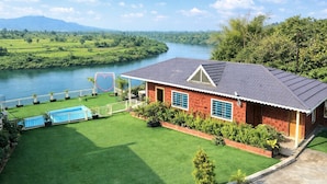 A house with a swimming pool, surrounded by a well-maintained lawn and a river view. - Necklace Bluewater Resort Bhor (Sangamner)