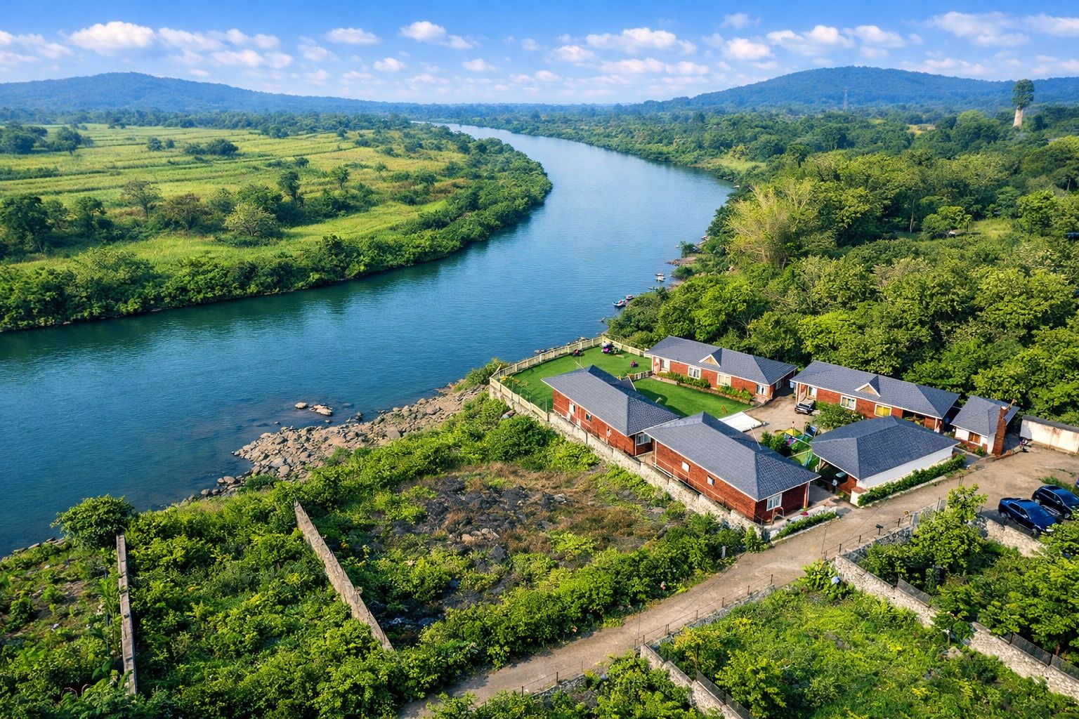 A riverside property with multiple brick houses, a well-maintained lawn, and a clear view of the river.