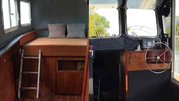A compact interior with a wooden bench, a ladder, and a steering wheel.