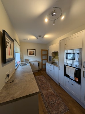A modern kitchen with white cabinets, a built-in microwave, and a stainless steel oven.