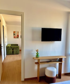 A room with a wooden bench, a small green vase, a white cushion, and a flat-screen TV mounted on the wall. - Boutique Apartment near the Sea with Rooftop Terrace – Santa Maria al Bagno (Nardò)