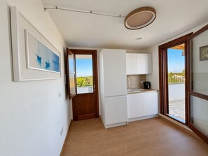 Una cocina moderna con armarios blancos, una puerta de madera y vistas al exterior.