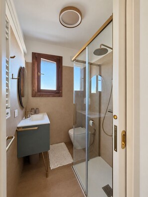 A modern bathroom with a glass shower enclosure, a vanity with a sink, and a toilet. - Boutique Apartment near the Sea with Rooftop Terrace – Santa Maria al Bagno (Nardò)