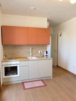 A compact kitchen with a built-in oven, a sink, and a coffee maker. - Boutique Apartment near the Sea with Rooftop Terrace – Santa Maria al Bagno (Nardò)