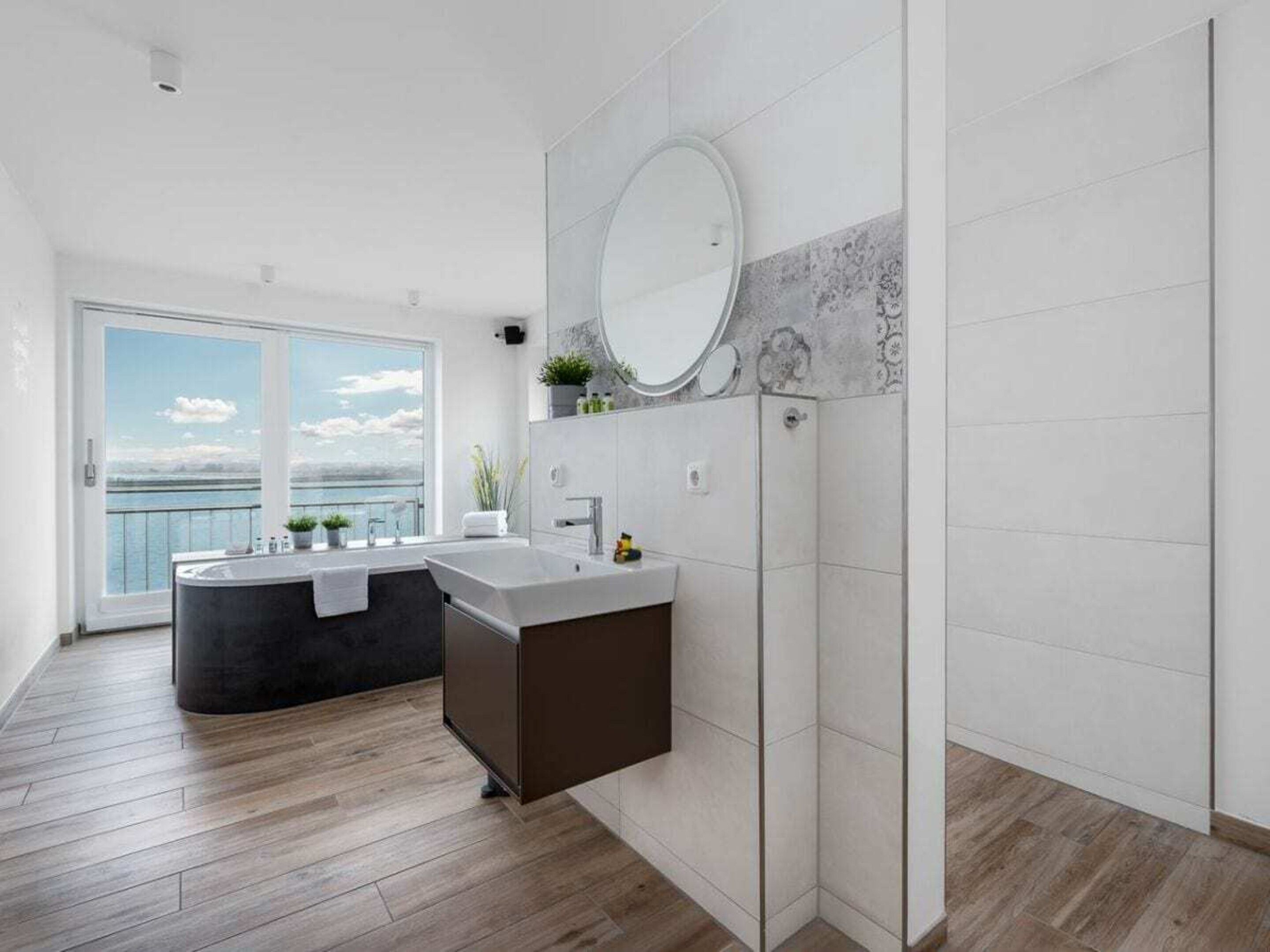 A modern bathroom with a large mirror, a bathtub, and a shower area.
