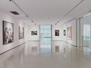 A spacious gallery with a polished floor, white walls, and artwork displayed on both sides. - Holiday Residence in North Vosges (Bitche)