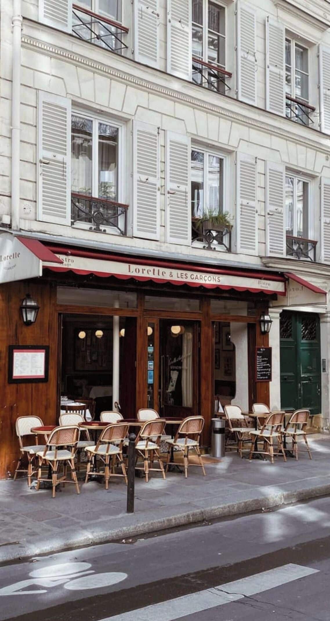 A cafe with outdoor seating, a red awning, and a sign reading 'Lorette & Les Garcons'.