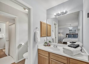 Une salle de bain moderne avec un grand miroir, un meuble-lavabo et un espace douche.