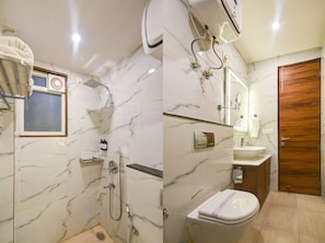 Een badkamer met douche, toilet, wastafel en een houten deur.