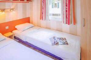 A single bed with a white mattress and pillows, a wooden headboard, a nightstand, and a window with curtains. - Spacious Family Haven in Istria (Brtonigla)