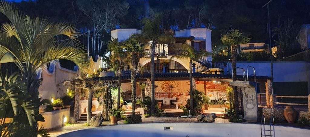 A multi-story building with a pool, palm trees, and outdoor lighting.