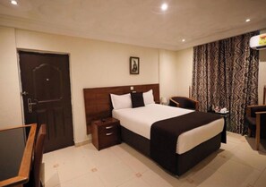 A hotel room with a large bed, bedside tables, a desk, and a chair. - Enjoyable 1-bedroom apartment with AC in vibrant Accra (Accra)