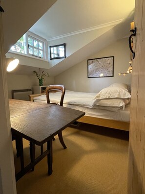 A small, cozy room with a single bed, a wooden chair, a table, and a window. - Beautiful coastal cottage in stunning National Trust Parkland with nearby beach! (Winchelsea)