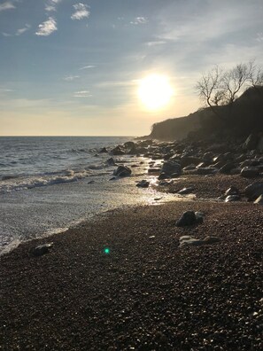 A pebbled beach with a rocky shoreline and a clear sky. - Beautiful coastal cottage in stunning National Trust Parkland with nearby beach! (Winchelsea)