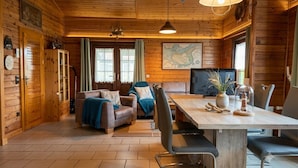Interior de una cabaña de madera con comedor, asientos y un mapa en la pared.