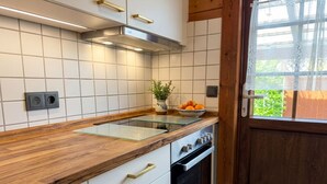 Una cocina con armarios blancos, encimera de madera, estufa y ventana con vistas a la vegetación.