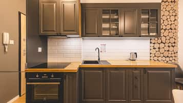 A modern kitchen with dark cabinetry, a wooden countertop, a stainless steel sink, and a built-in oven.