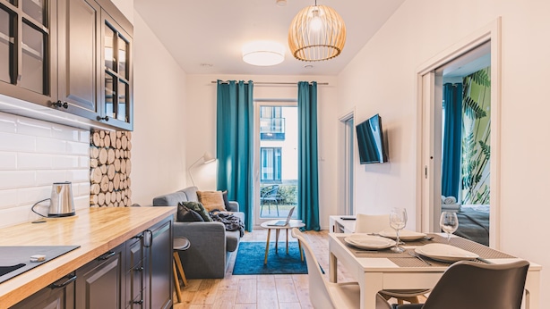 Una cocina compacta con cafetera, una zona de comedor con una mesa para dos personas y un sofá.