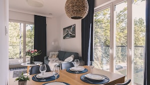 Un comedor con una mesa de madera dispuesta para cuatro personas, un sofá y un cuadro en la pared.