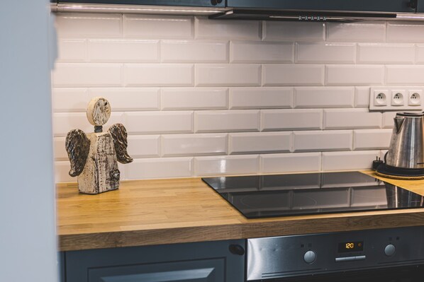A kitchen with a wooden countertop, a stainless steel kettle, and a digital oven control panel.