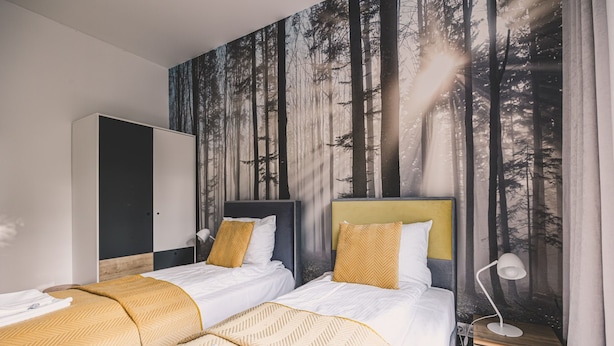 A bedroom with two beds, a wardrobe, and a mural of a forest. - Bisonte Apartament 2 Sypialnie Du y Taras (Hajnowka)