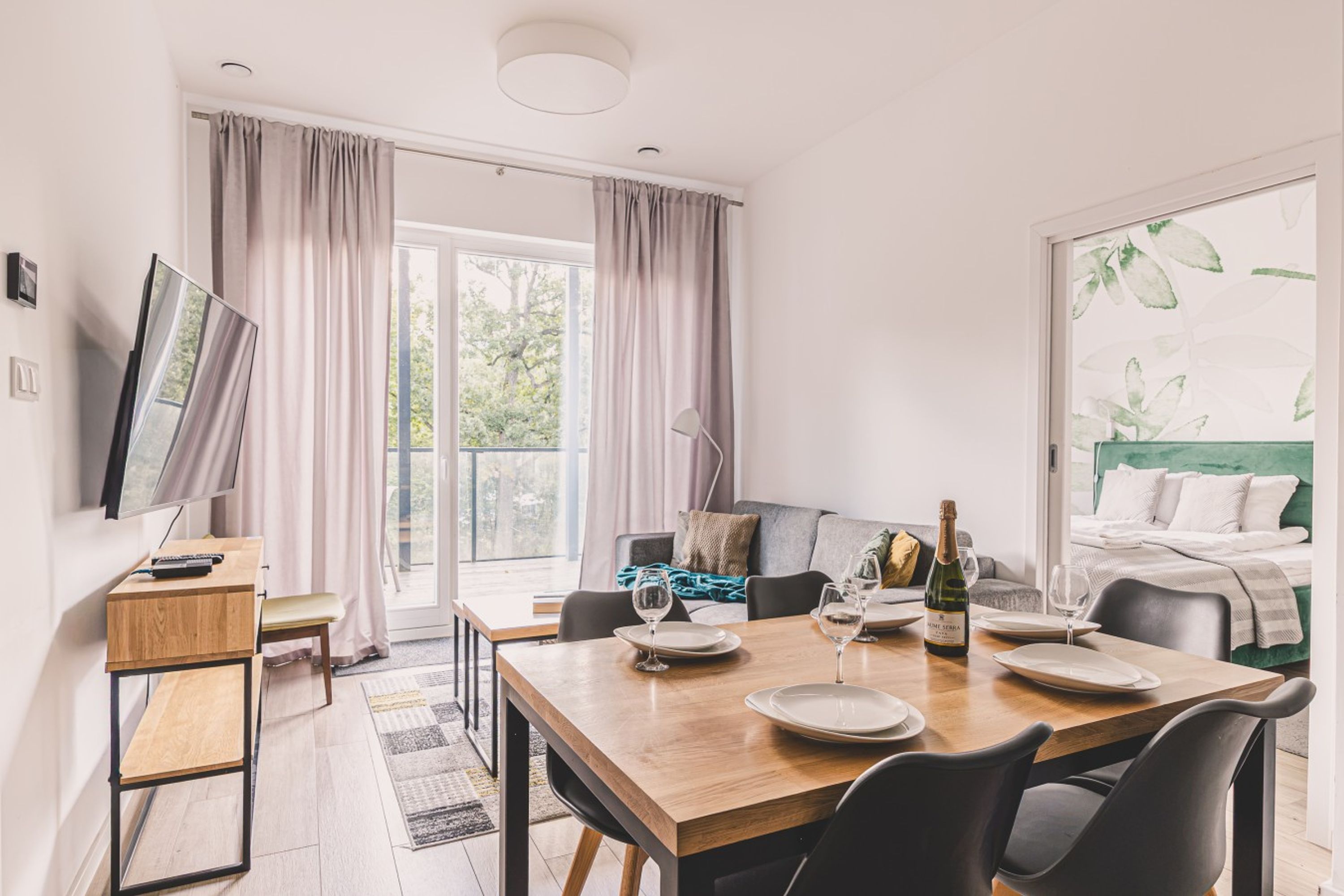 Una sala de estar moderna con una mesa de comedor, sillas, un sofá y un televisor.