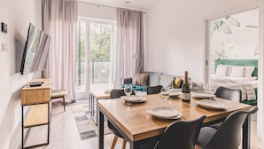 A modern living room with a dining table, chairs, a sofa, and a TV. - Bisonte Apartament 2 Sypialnie Du y Taras (Hajnowka)