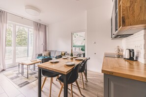 A modern kitchen with wooden countertops, a dining area with a table set for four, and a view of a green landscape through the window.