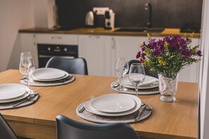 A dining table set with plates, glasses, and cutlery, with a vase of flowers on the table.