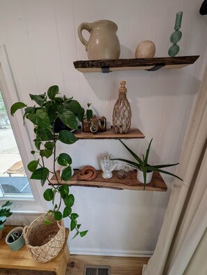Una estantería con una jarra de cerámica, una botella de madera y una pequeña planta.