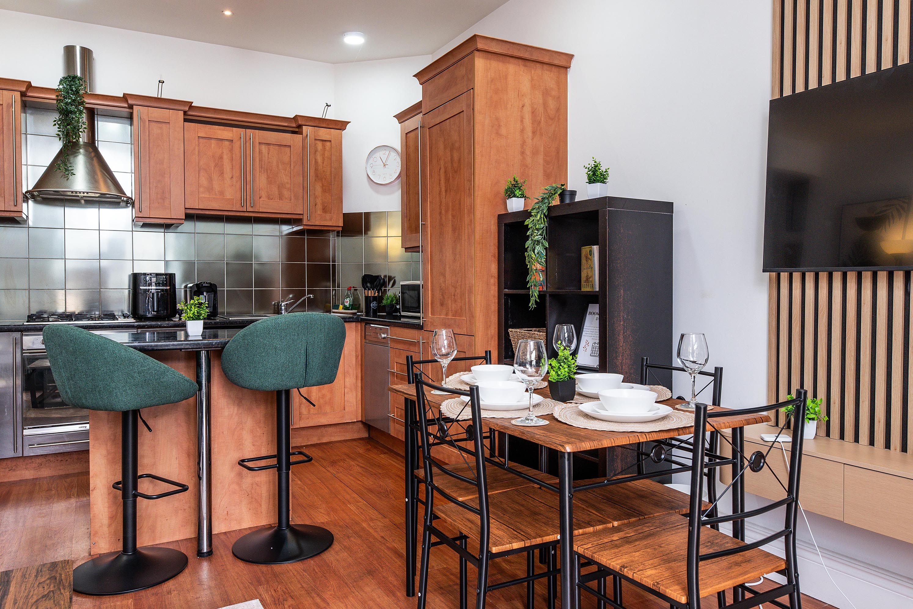 Una cocina moderna con armarios de madera, estufa de acero inoxidable y un comedor con mesa lista para dos.