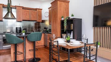 Una cocina moderna con armarios de madera, estufa de acero inoxidable y un comedor con mesa lista para dos.